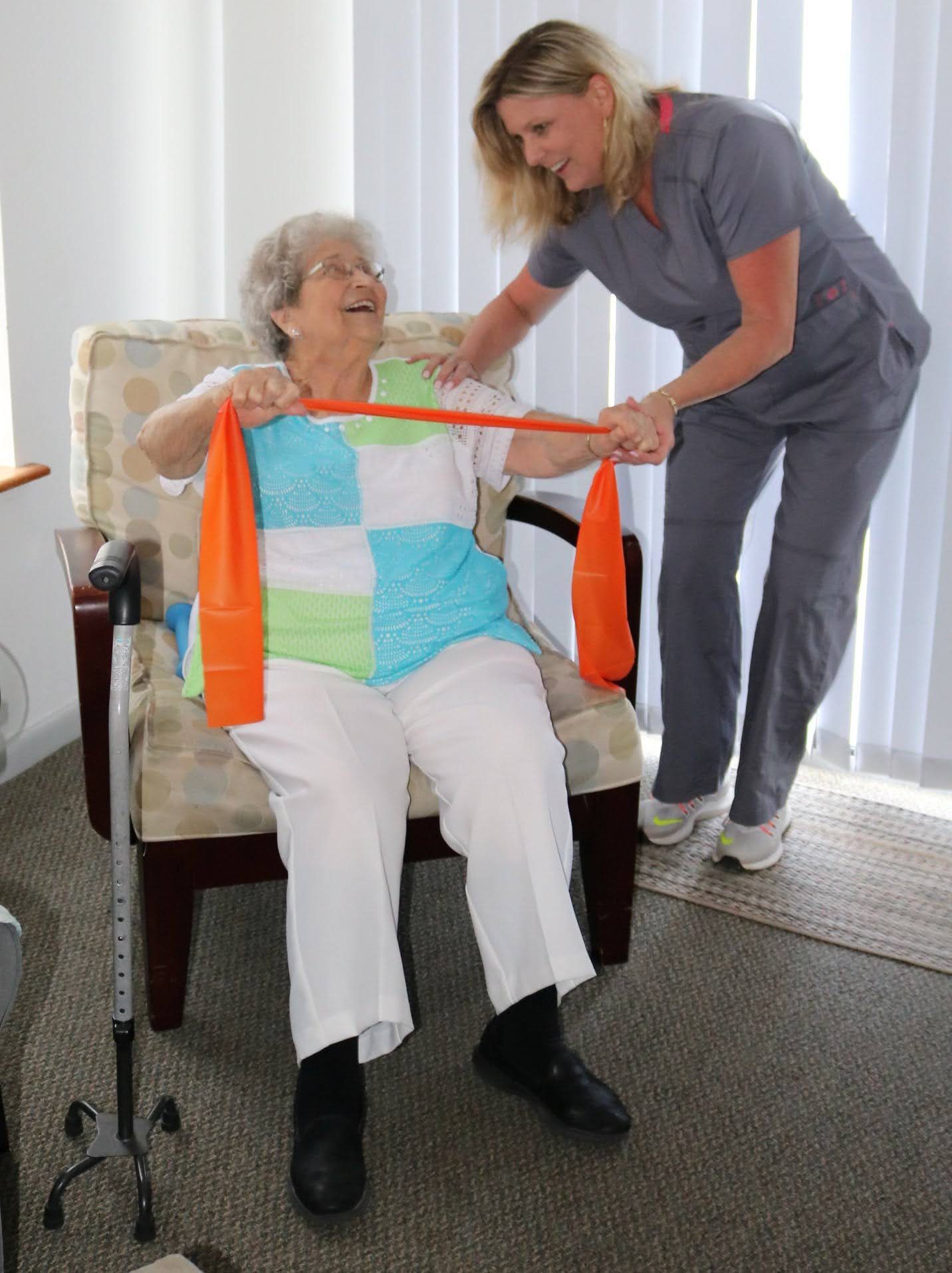 A therapist helping a smiling resident with a resistance band exercise