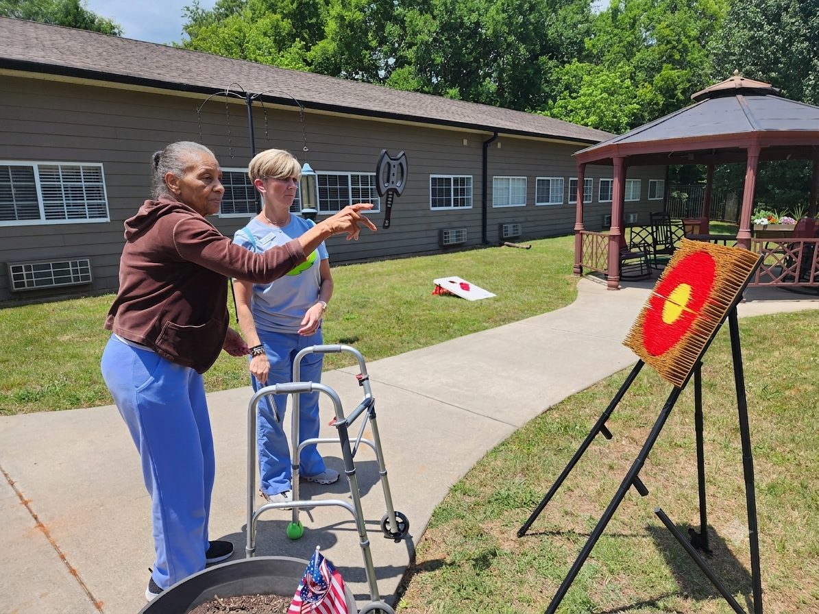 A resident aiming at an axe-throw target outdoors with a therapist's support